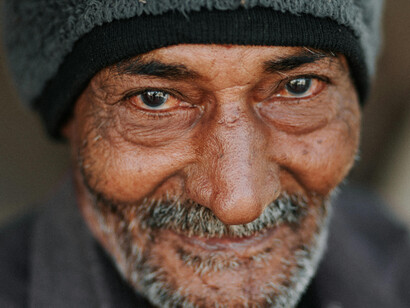 An old, weary man smiling warmly