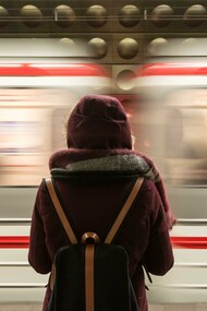 A woman standing alone in front of a fast-riding train