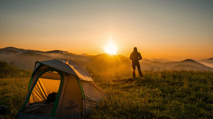 A person camping surrounded by nature, representing the balance many seek between technology and well-being