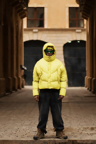 A young man wearing an oversized puffer jacket and wide-leg pants, embracing a trendy look