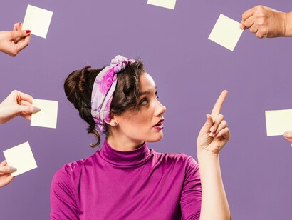 Donna circondata da mani con post-it: "Fare tanto è meglio che fare meno, o almeno così sembra, a noi comuni mortali, ai nostri datori di lavoro -lavoratori autonomi o dipendenti che siamo- ma soprattutto agli osannati esperti di produttività, spuntati come funghi dopo la pioggia"