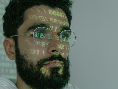 A man deeply entrenched in the AI as a binary code surfaces on his face