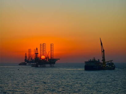 Oil rigs at the horizon at dusk, symbolizing the industries whose emissions have fueled the climate crisis
