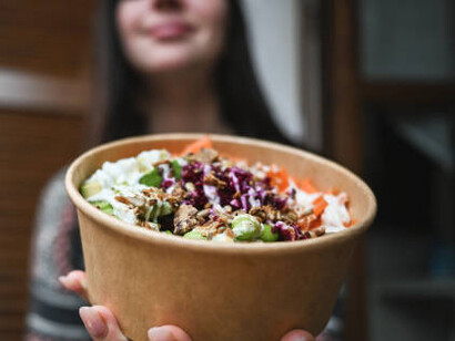 A woman savoring a seafood salad, wrapped in eco-friendly edible packaging, highlighting the future of sustainable food storage