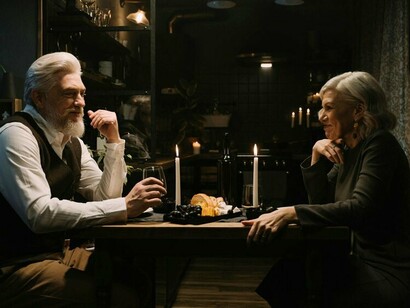 An old couple meeting each other’s eyes across the table, displaying a love that endures beyond passion