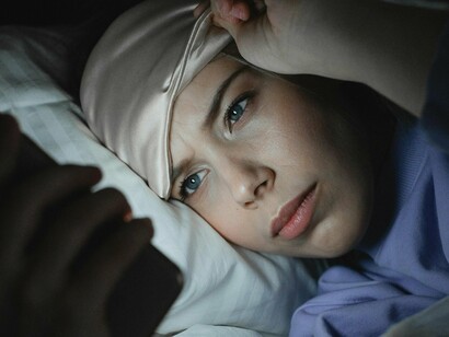 Mulher mexe em seu celular no momento de dormir. A privação de sono, portanto, interfere diretamente nesses processos. Quando não dormimos o suficiente, o corpo não consegue se recuperar adequadamente, e o cérebro não tem a oportunidade de consolidar memórias ou processar emoções. O resultado é um declínio no desempenho cognitivo, emocional e físico. Estudos mostram que pessoas que dormem menos de seis horas por noite têm maior dificuldade de concentração, tomam decisões menos acertadas e são mais propensas a erros. Além disso, a privação de sono está associada a um aumento nos níveis de estresse, ansiedade e depressão