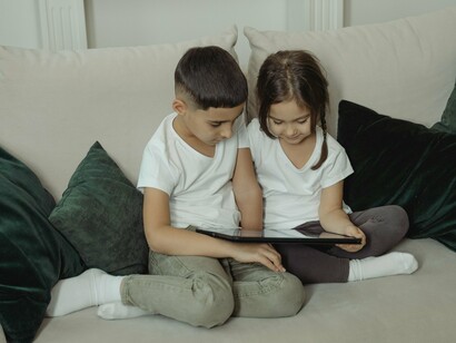 Uma menina e um menino utilizam juntos um dispositivo digital, concentrados naquilo que aparece diante deles. Mais do que oferecer acesso individual à informação, a tecnologia também pode se tornar instrumento de interação, descoberta e aprendizagem compartilhada