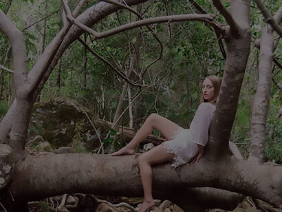 A young woman reclines gracefully on a tree trunk, embodying a sense of tranquility and natural beauty