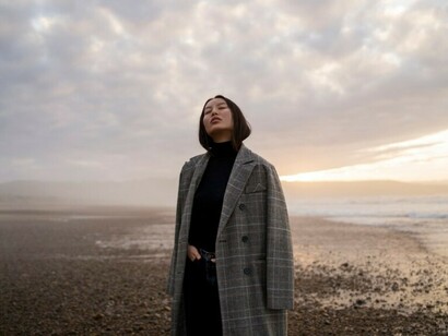 A solitary woman gazes out at the sea, lost in wistful memories