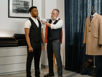 A tailor taking precise measurements, symbolizing the craftsmanship that makes an attractive design into something that can actually be produced