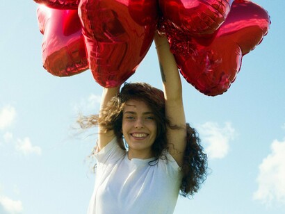 Mulher com balões em forma de coração. Jung sugeriu que encontros amorosos muitas vezes envolvem uma sincronicidade, refletindo uma conexão profunda entre os indivíduos no nível inconsciente. O amor, assim, é um fenômeno que transcende a lógica e a razão, envolto em mistério e significado simbólico