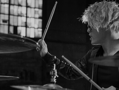 A man in a black jacket showcasing his drumming skills