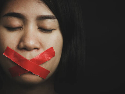 A young woman with adhesive tape sealing her mouth portrays the silencing effect of censorship, highlighting the ongoing fight for freedom of speech and press