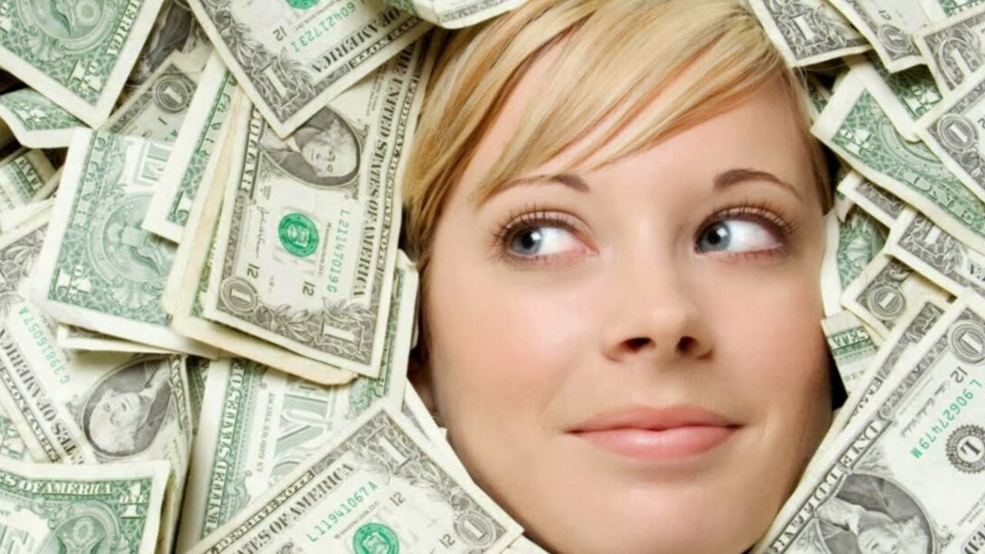 Una mujer nadando sumergida entre billetes de dólares