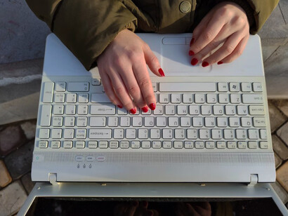 A person is working on a laptop, typing on the keyboard with focus and intent