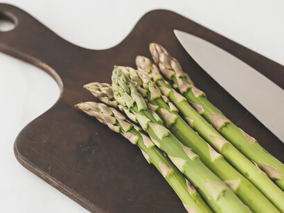 On a rustic cutting board, a tasteful arrangement unfolds as asparagus gracefully complements a bed of bread, creating a visually enticing scene that celebrates both culinary finesse and the vibrant simplicity of natural ingredients