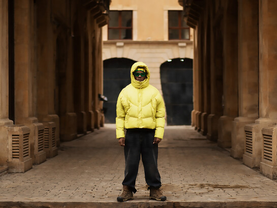 A young man wearing an oversized puffer jacket and wide-leg pants, embracing a trendy look