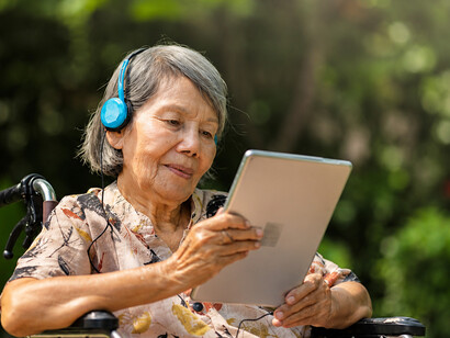 An elderly woman enjoys music therapy through headphones, illustrating the power of familiar melodies and earworms in supporting memory, mood, and cognitive wellbeing in dementia care