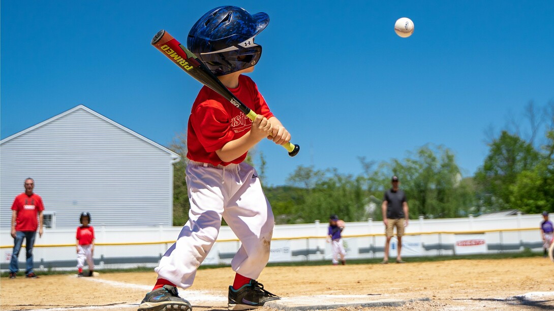 A young boy gripping his bat with determination, reflecting the early spark of competitive spirit