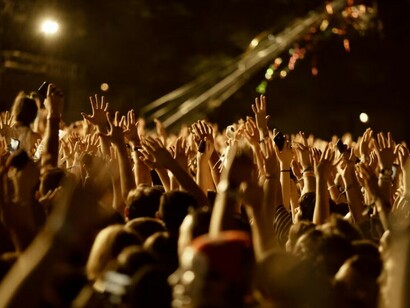 Thousands of fans raise their arms in excitement, dancing to the beat at a nighttime music festival
