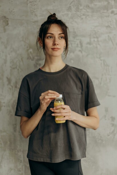 A fitness influencer holding a bottle of juice after a gym workout, symbolizing healthy lifestyle content often shared on social media