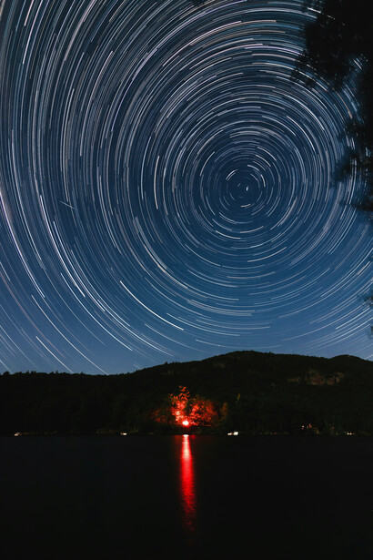 Time-lapse photo of glowing mountain lights under a starry sky, with galaxies and the expansive universe stretching overhead