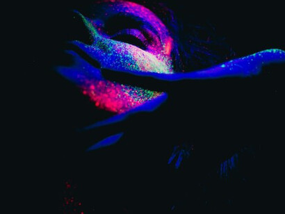 A woman's countenance embellished with a kaleidoscope of colored powders, crafting a mesmerizing and vivid portrait