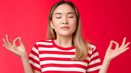 A young woman practicing meditation and deep breathing against a red background for stress relief and relaxation