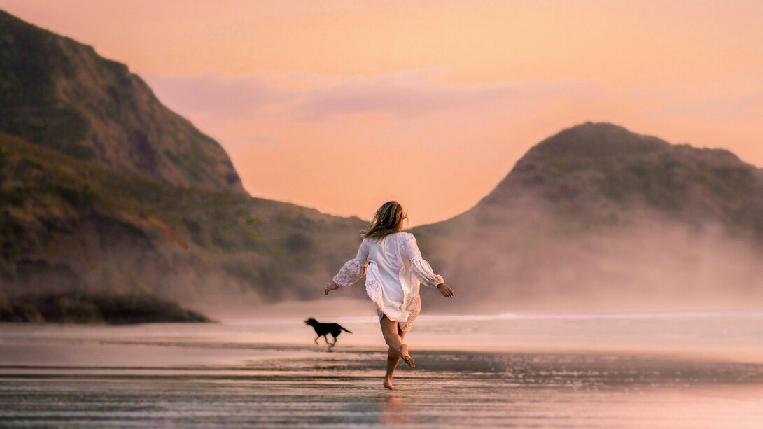 Une femme qui court sur la plage avec un chien apprécie le goût de la liberté