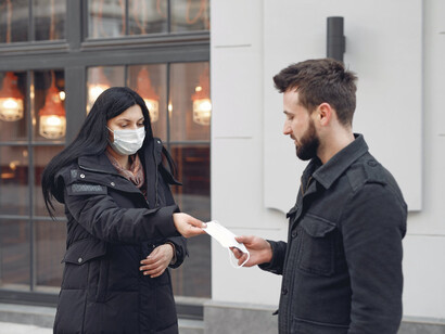 Ragazza porge ad un amico una mascherina mentre passeggia per strada