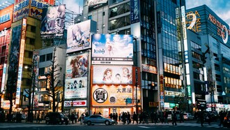 A bustling Tokyo district surrounded by towering anime billboards and media advertisements, symbolising the cultural prominence anime and manga have achieved in Japan and beyond