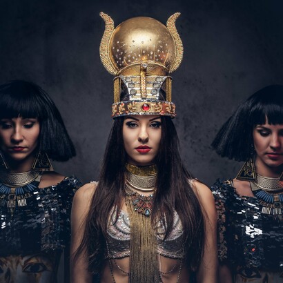 A woman wearing a lavish crown and striking makeup echoes the grandeur of historical monarchs, reminding us of the powerful role queens played in setting beauty standards