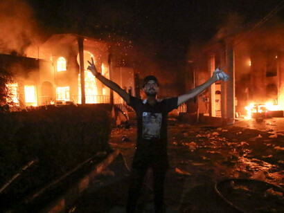 An Iraqi protester stands flashing the victory gesture outside the burning headquarters of the Iranian Consulate in Basra 