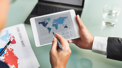 Economists analyzing data on a screen filled with global charts