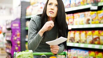 Una chica comprueba la lista de la compra en el supermercado