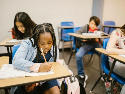 Young girl writing diligently in class