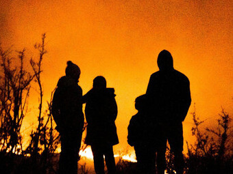 A family observes a distant wildfire during the summer of 2020, witnessing the destructive force of extreme weather