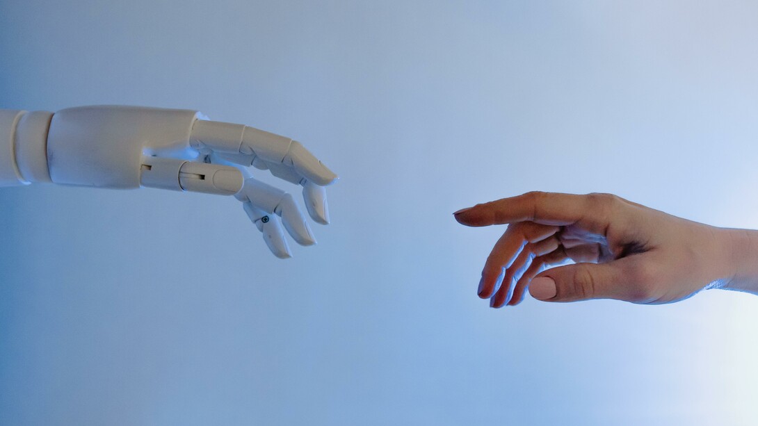 Mão de robô representando a inteligência artificial e mão de um humano
