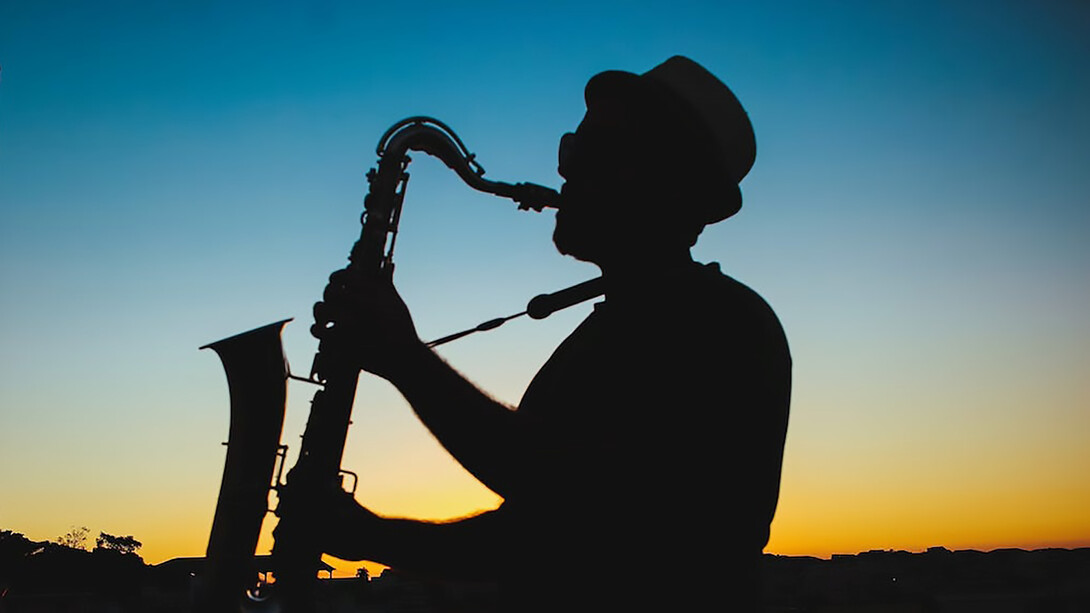 Silhouette of a man playing saxophone during sunset