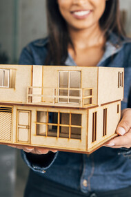 Smiling African American woman holding a model of a portable house