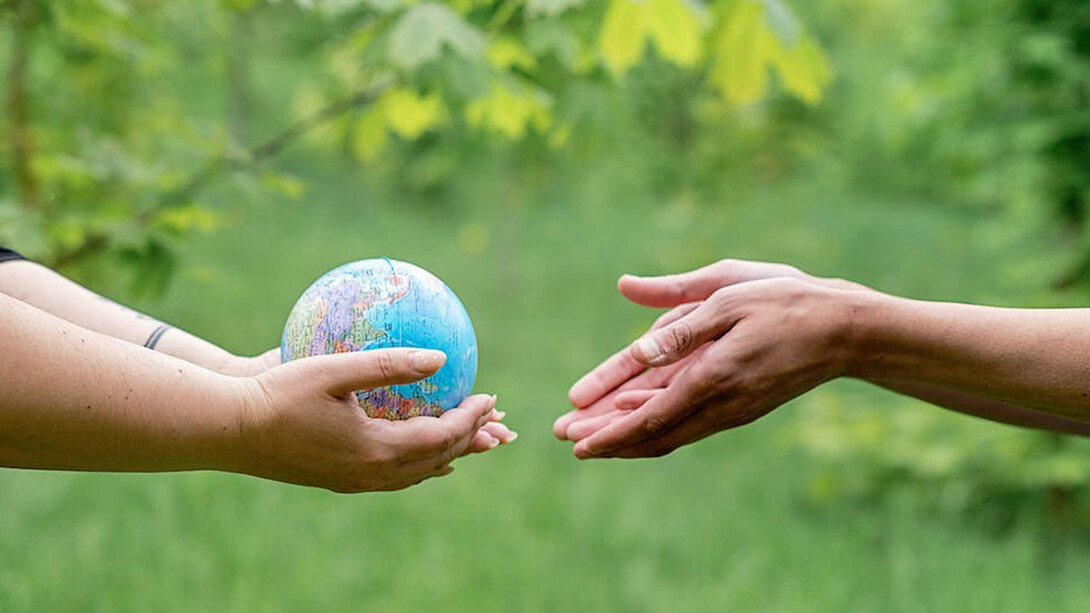 Two individuals embracing the world globe as a symbol of global unity and responsibility