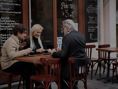 The charm of a family-run restaurant with smiling patrons enjoying drinks in a cozy bistro setting