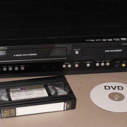 A vintage television with a vcr tape and dvd aside it