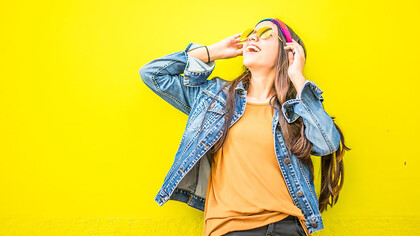 A woman is smiling in front of a yellow wall