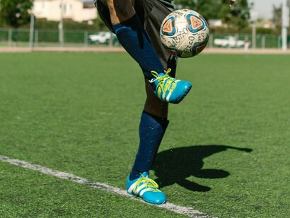 Crampons aux pieds, un joueur s'entraîne et s'amuse avec le ballon