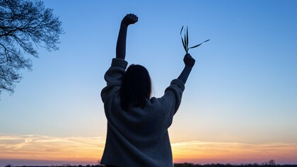 With arms raised in freedom and a sprig of life in hand, she embodies the power of simple, intentional choices to move, eat, and thrive toward a vibrant and healthy future