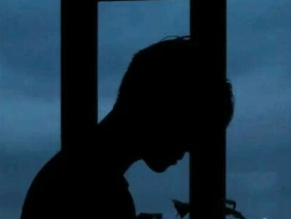 Persona di profilo da sola davanti una finestra di sera 