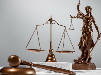 A judge's gavel resting before the scales of justice and Lady Justice, symbolizing the foundation of legitimacy through proportional legal order