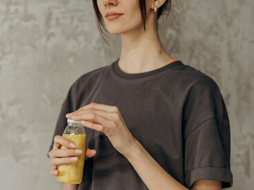 Woman holding a bottle of juice after a gym session, reflecting the healthy lifestyle often promoted by fitness influencers