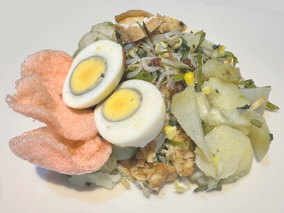 The crispy krupuk and fried shallots on top of the gado-gado add an irresistible crunch, perfectly complementing the rich, savoury peanut sauce in this close-up view of the beloved salad